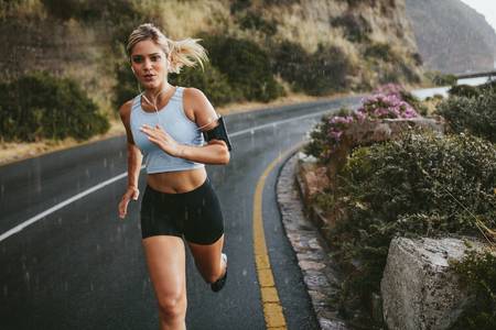 60944730-female-athlete-running-outdoors-on-highway-beautiful-young-woman-training-running-on-a-rainy-day-.jpg